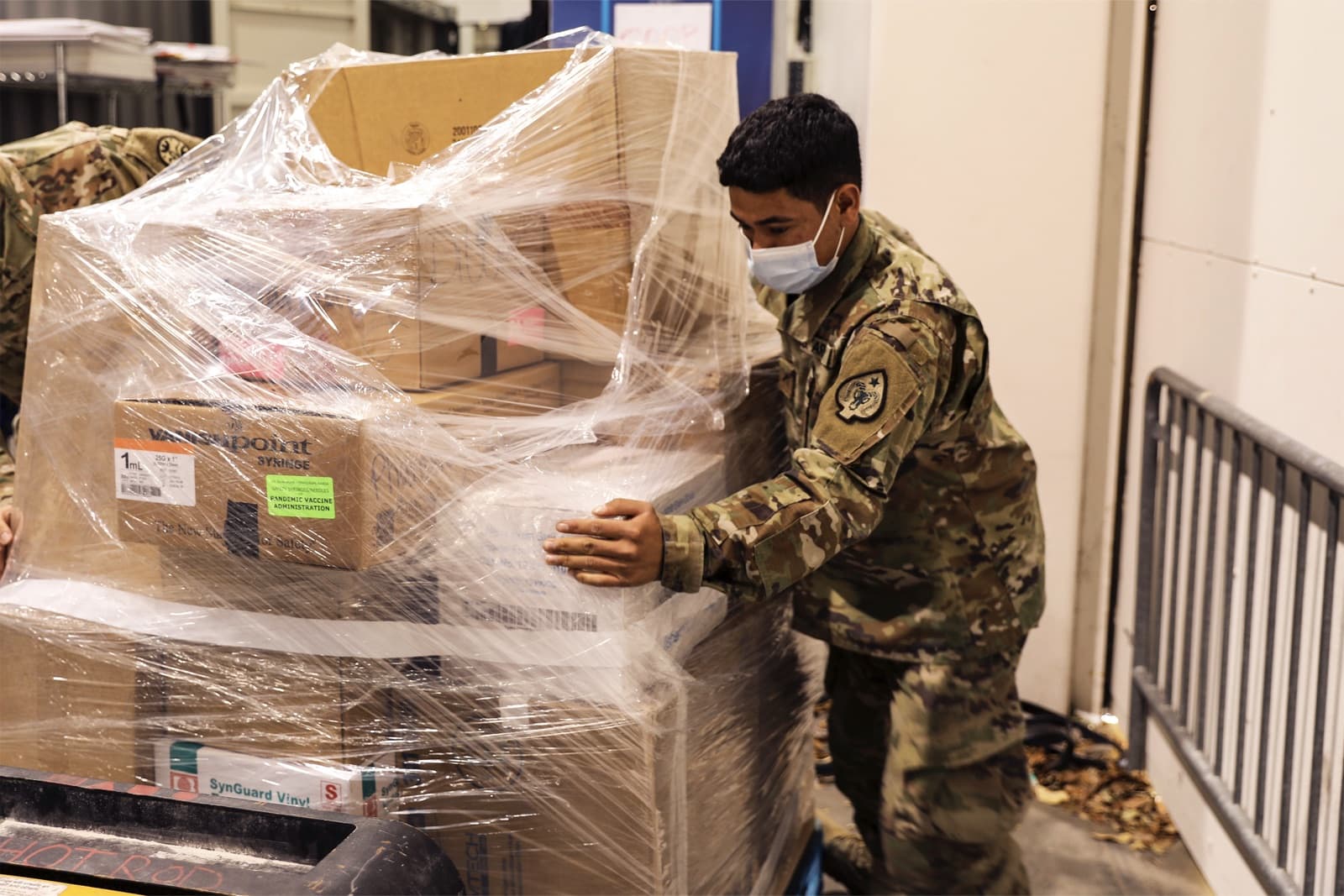 Service member handling palletized medical supplies in a warehouse